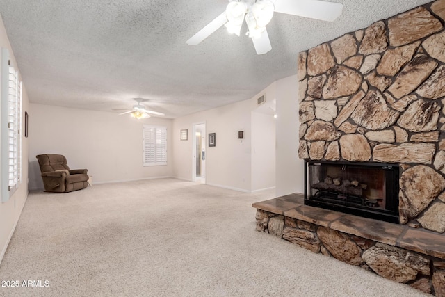 living room with carpet, ceiling fan, a fireplace, and a textured ceiling