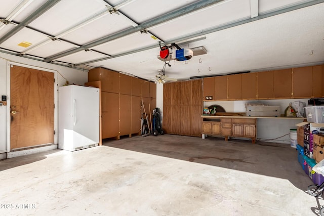 garage featuring white refrigerator and a garage door opener