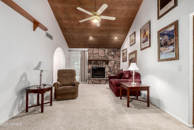 carpeted living room featuring wooden ceiling, lofted ceiling, a stone fireplace, and ceiling fan