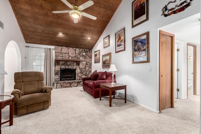 carpeted living room with ceiling fan, wooden ceiling, lofted ceiling, and a stone fireplace