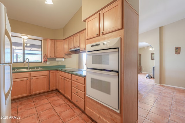 kitchen featuring light brown cabinetry, white appliances, light tile patterned flooring, and a sink