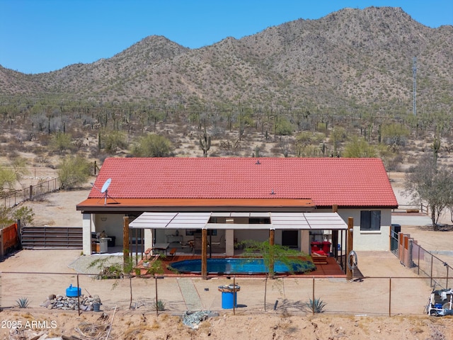 rear view of house featuring stucco siding, a fenced in pool, a tile roof, a patio area, and a mountain view