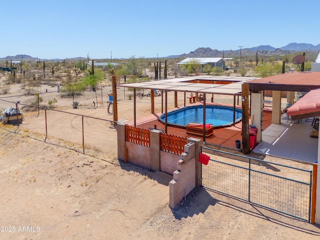 view of swimming pool with a mountain view, fence, and a jacuzzi