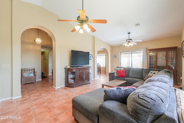 living area featuring light tile patterned floors, visible vents, ceiling fan, arched walkways, and vaulted ceiling