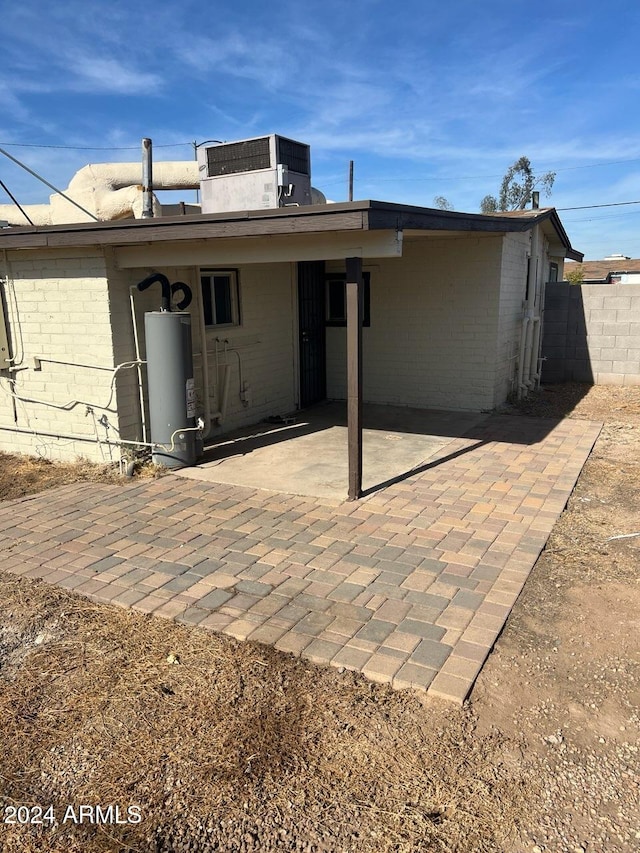 rear view of house with central air condition unit, a patio area, and gas water heater