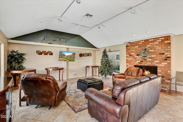 living room featuring rail lighting, a brick fireplace, vaulted ceiling, a textured ceiling, and light tile patterned flooring