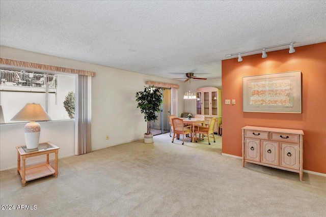 interior space featuring a textured ceiling, ceiling fan, light colored carpet, and rail lighting