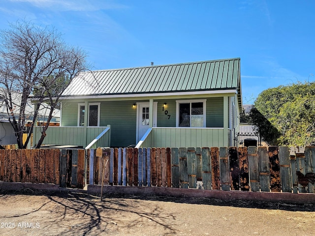 view of front of property with covered porch, metal roof, and a fenced front yard