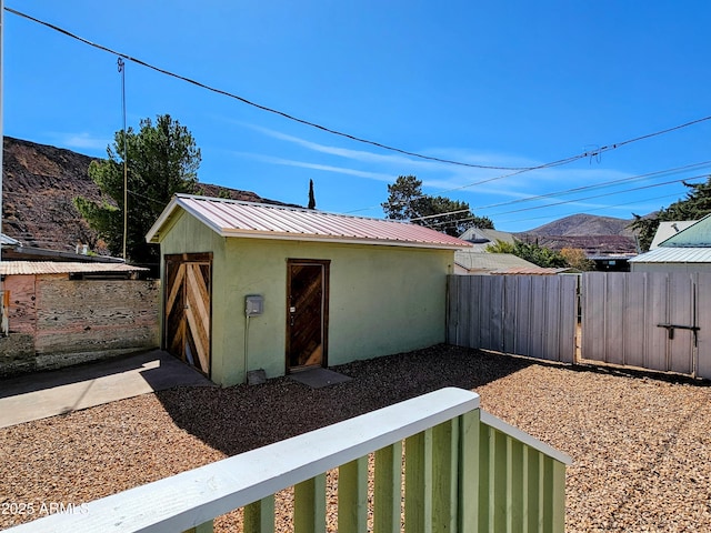 view of outdoor structure featuring a gate, fence, a mountain view, and an outdoor structure