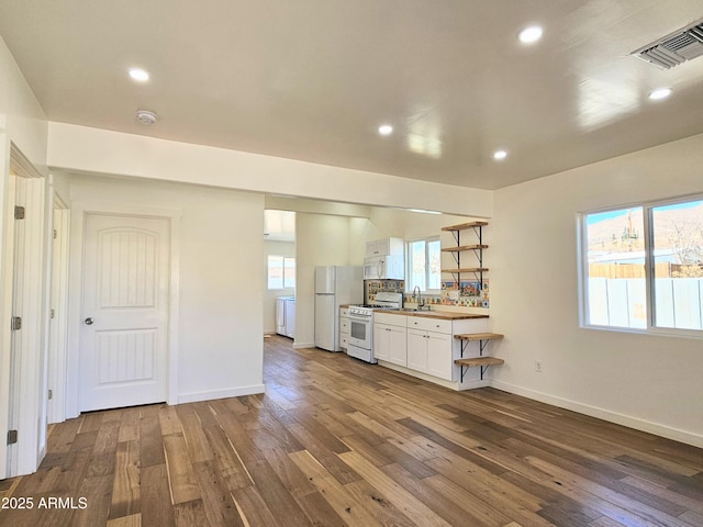 kitchen featuring white appliances, visible vents, white cabinets, dark wood-style floors, and a sink