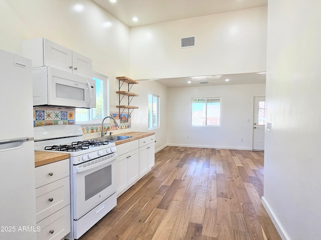 kitchen featuring visible vents, a sink, wood counters, light wood-type flooring, and white appliances