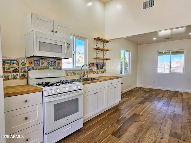 kitchen featuring white appliances, a sink, wood counters, visible vents, and dark wood-style floors