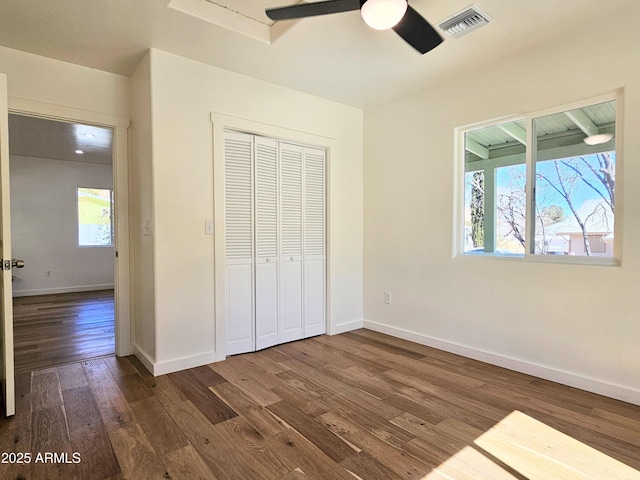 unfurnished bedroom featuring a closet, dark wood finished floors, visible vents, and baseboards