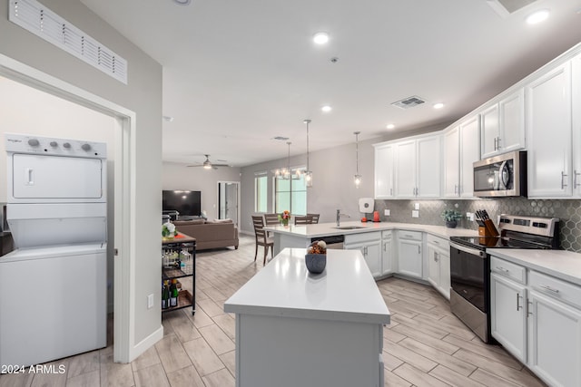 kitchen with stainless steel appliances, stacked washer / dryer, a sink, and backsplash