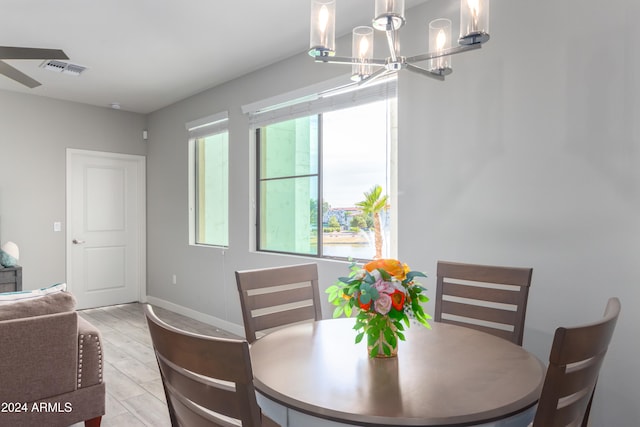 dining room featuring ceiling fan with notable chandelier and light hardwood / wood-style floors