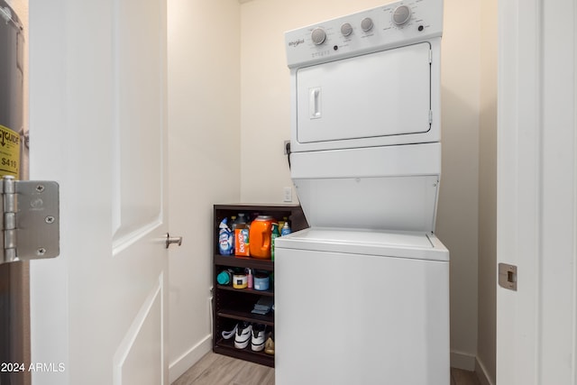 washroom with laundry area, baseboards, light wood-style flooring, and stacked washing maching and dryer