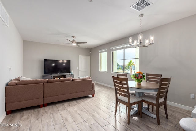 dining space featuring light hardwood / wood-style floors and ceiling fan with notable chandelier