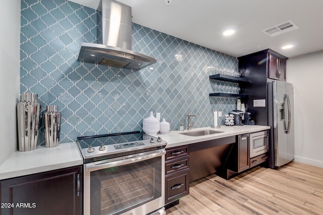 kitchen featuring stainless steel appliances, sink, wall chimney range hood, dark brown cabinets, and light hardwood / wood-style flooring