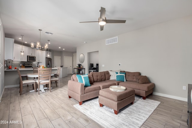 living room featuring ceiling fan with notable chandelier and light hardwood / wood-style floors