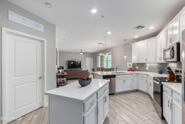 kitchen featuring visible vents, appliances with stainless steel finishes, open floor plan, a sink, and a peninsula