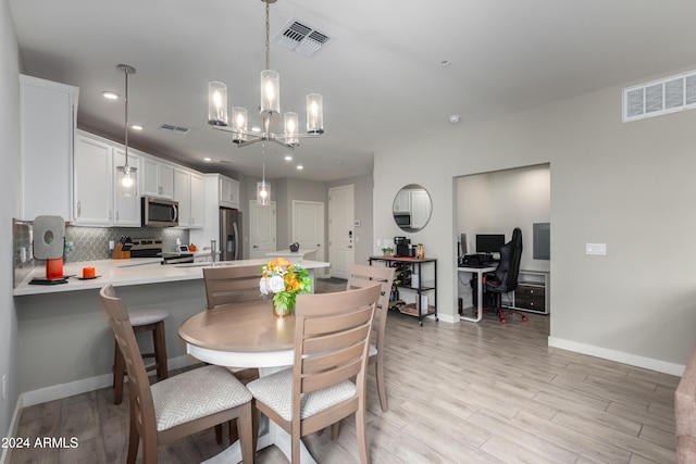 dining space featuring light wood-type flooring, sink, and an inviting chandelier