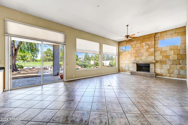 unfurnished living room featuring tile patterned floors, plenty of natural light, ceiling fan, and a tiled fireplace