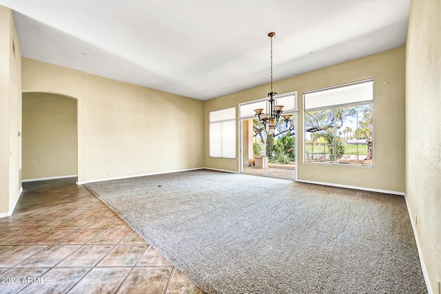 carpeted spare room with a notable chandelier