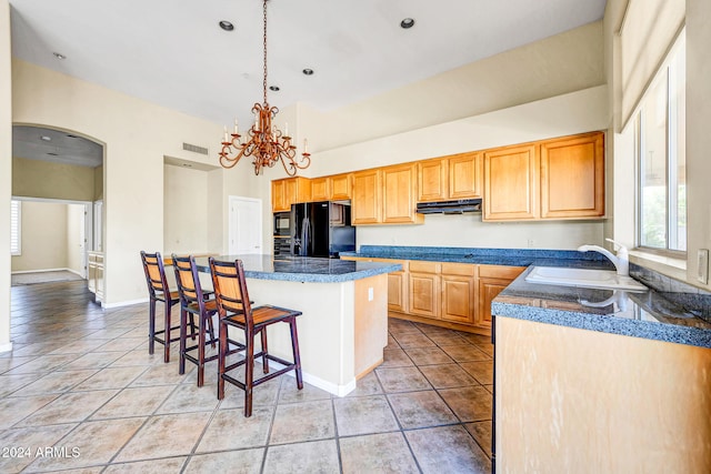 kitchen with extractor fan, black appliances, sink, a center island, and a breakfast bar area