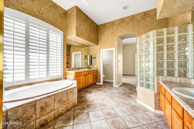 bathroom with tile patterned floors, vanity, toilet, and tiled tub