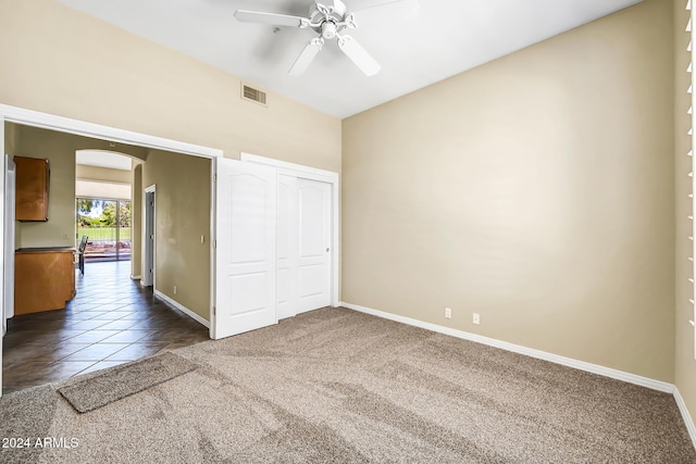 unfurnished bedroom featuring ceiling fan, a closet, and dark colored carpet