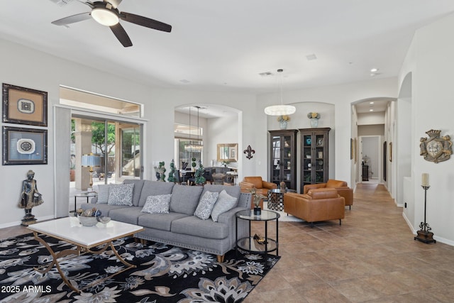 living area with arched walkways, ceiling fan, baseboards, and recessed lighting