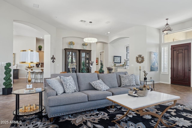 living room featuring arched walkways, tile patterned flooring, baseboards, and a towering ceiling