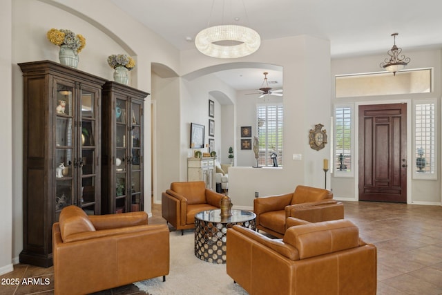 foyer with arched walkways, a ceiling fan, baseboards, and tile patterned flooring