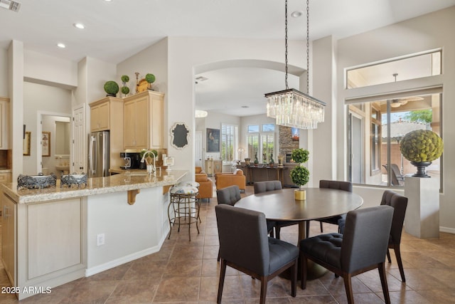 dining room with arched walkways, baseboards, recessed lighting, a high ceiling, and a chandelier