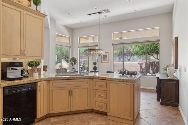 kitchen featuring dishwasher, a sink, light brown cabinets, and plenty of natural light
