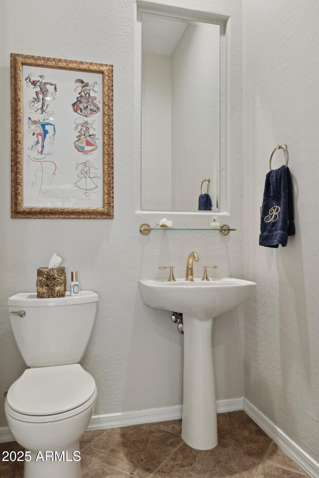 half bath featuring toilet and baseboards
