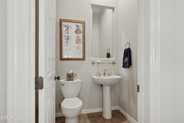 half bath featuring toilet, tile patterned floors, and baseboards