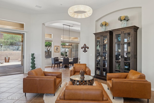 sitting room with arched walkways, tile patterned flooring, baseboards, and a towering ceiling