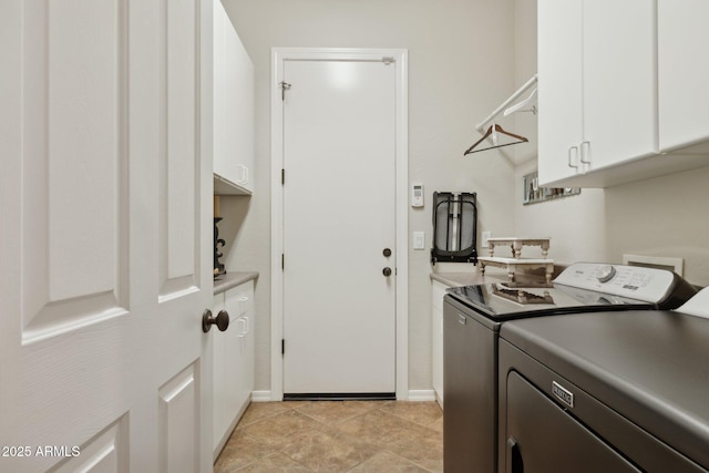 washroom with cabinet space, washing machine and clothes dryer, and baseboards