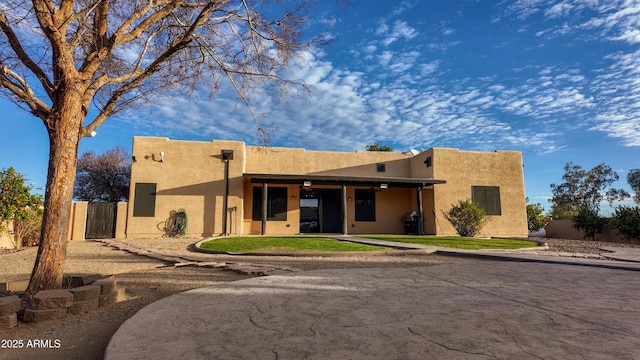 pueblo revival-style home with fence and stucco siding