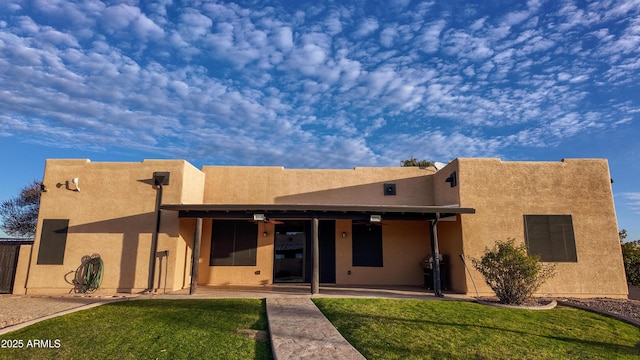 view of front of home featuring stucco siding, a patio area, and a front yard