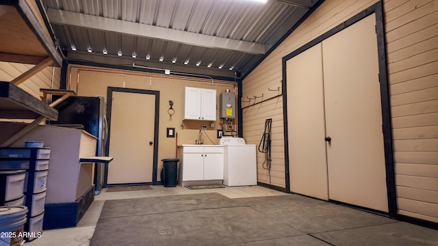 garage with water heater, wood walls, a sink, and washing machine and dryer