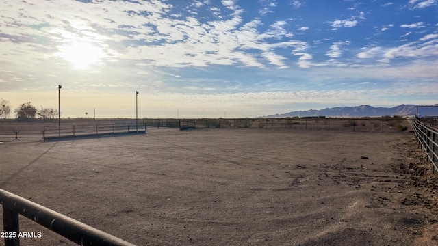 view of yard featuring an enclosed area, a rural view, fence, and a mountain view