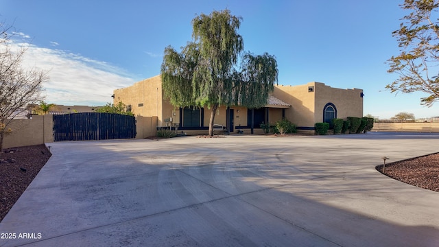 southwest-style home featuring a gate, fence, and stucco siding