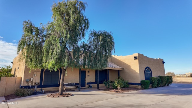 pueblo revival-style home with fence and stucco siding