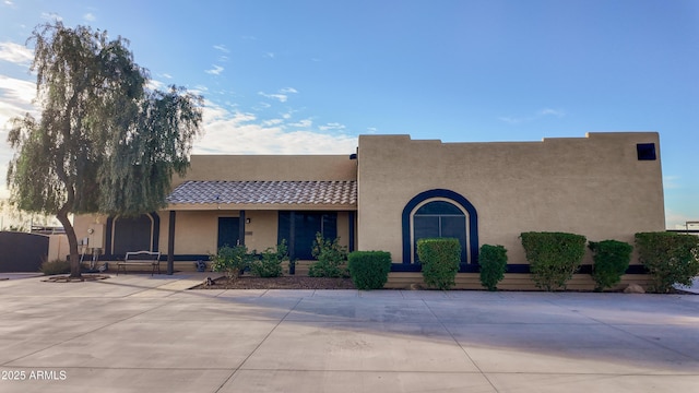 adobe home featuring a patio, a tiled roof, and stucco siding