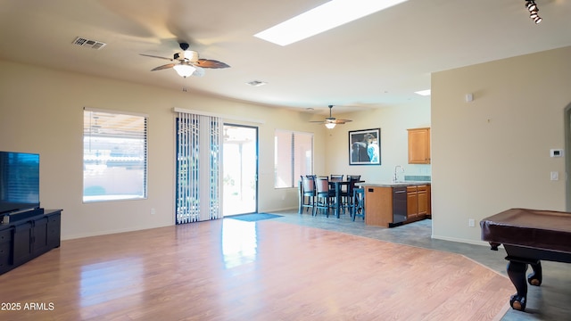 living area with light wood-style floors, visible vents, ceiling fan, and baseboards