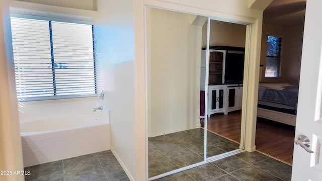 ensuite bathroom with a garden tub, tile patterned flooring, and connected bathroom