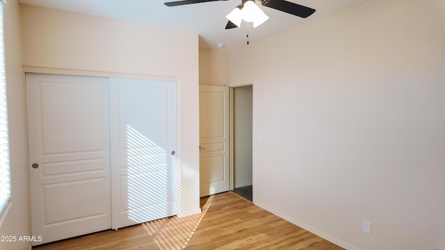 unfurnished bedroom featuring baseboards, a closet, a ceiling fan, and light wood-style floors