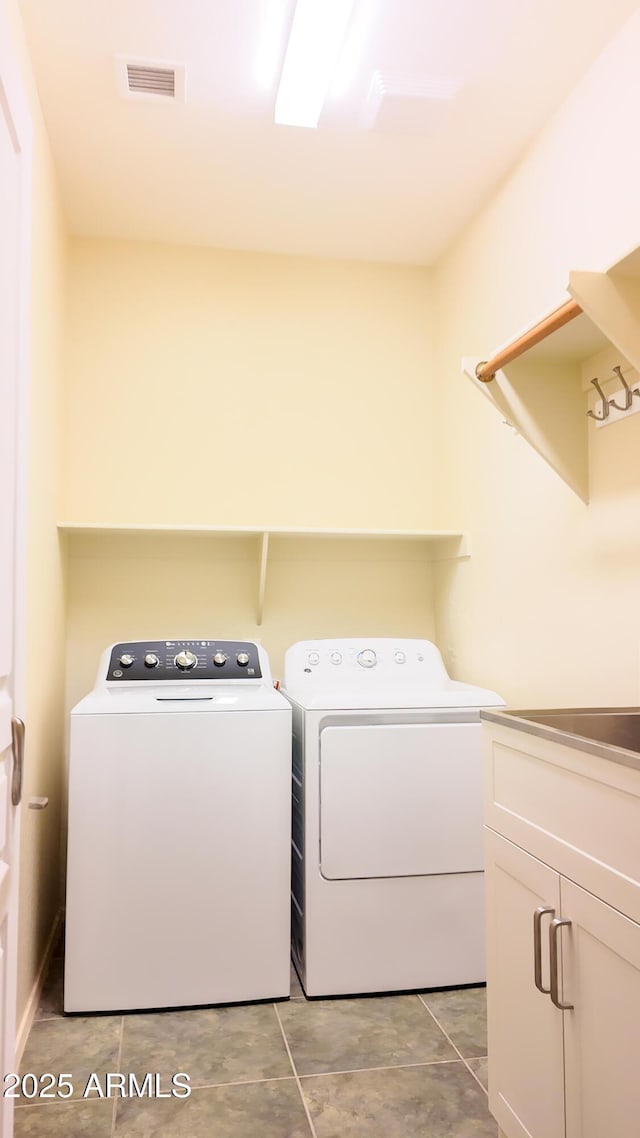 clothes washing area with cabinet space, visible vents, and washing machine and clothes dryer